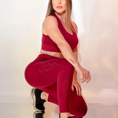 Mulher com roupa desportiva bordô e sapatilhas pretas em fundo branco