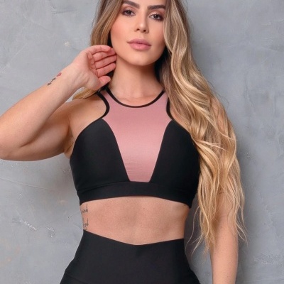 Top desportivo rosa e preto com leggings pretas em fundo cinzento.