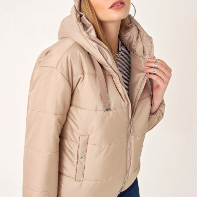 Mulher com casaco acolchoado beige e gorro bege