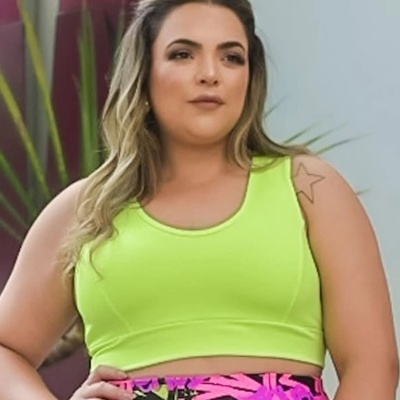 Mulher com top desportivo amarelo fluorescente e leggings coloridas abstratas.