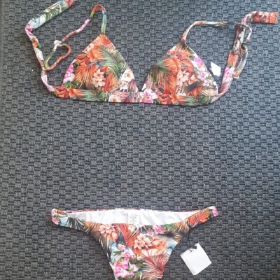 Biquíni estampado tropical colocado sobre superfície cinzenta texturada