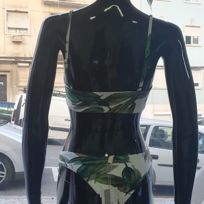 Manequim com fato de banho estampado de folhas verdes e chapéu de palha com laço
