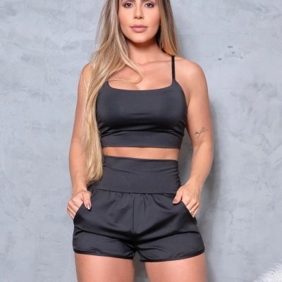 Conjunto feminino preto com crop top e calções com bolsos em fundo cinzento