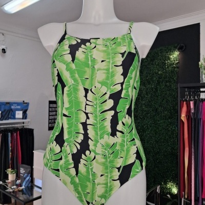Fato de banho com padrão de folhas verdes e fundo preto em manequim branco na loja.