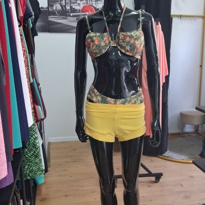 Mannequim com top de bikini floral e calções amarelos numa loja de roupa.
