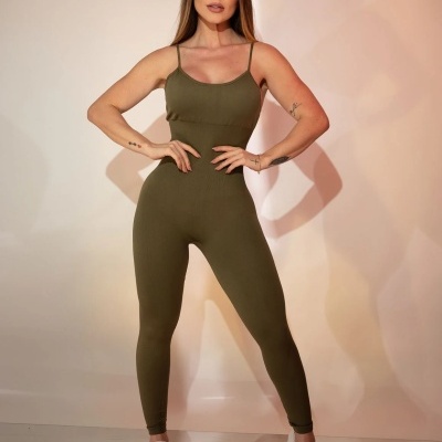 Mulher com macacão verde-oliva justo e sapatilhas brancas em fundo claro.