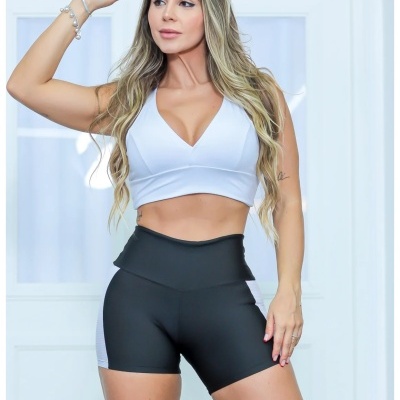 Mulher a usar conjunto de roupa desportiva com top branco e leggings pretas curtas.