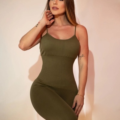 Mulher com macacão verde-oliva de alças finas frente a fundo claro