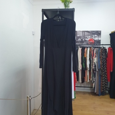 Vestido comprido preto de manga comprida pendurado em cabide num suporte preto