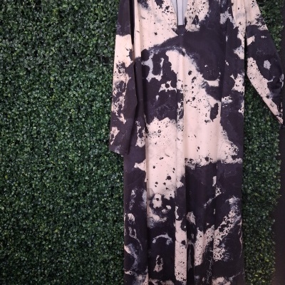 Vestido com padrão tie-dye preto e bege pendurado numa parede verde