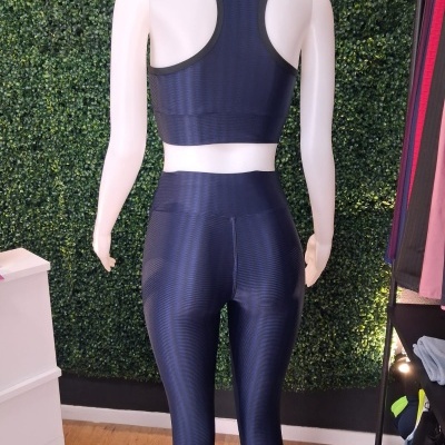 Conjunto desportivo azul escuro com padrão de linhas horizontais em manequim branca visto de costas