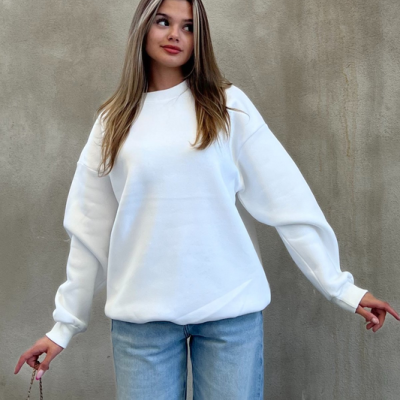 Mulher com sweatshirt branca, calças de ganga azuis claras e bolsa preta com alça dourada