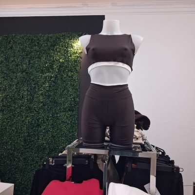 Conjunto fitness preto com top cropped e calções exposto num manequim branco em loja com fundo verde e branco
