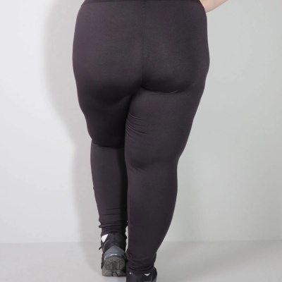 Leggings pretas elásticas com cintura alta vistas de trás num modelo com ténis desportivos.
