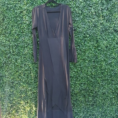 Vestido longo de algodão cinzento escuro com mangas compridas pendurado numa parede verde