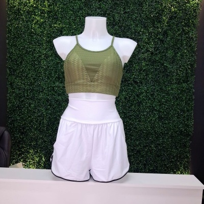 Conjunto desportivo verde e branco exibido num manequim com fundo verde