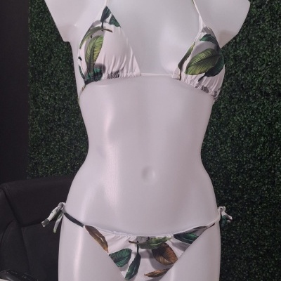 Biquíni branco com folhas verdes e castanhas num manequim branco