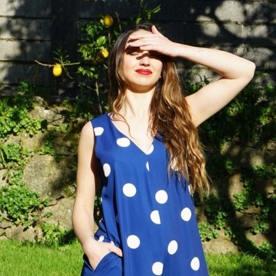 Mulher com vestido azul de bolinhas brancas em jardim com limoeiro