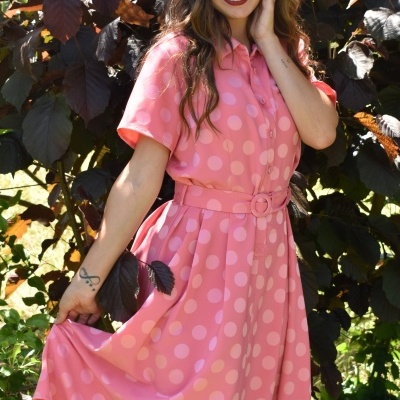 Vestido cor-de-rosa com padrão de bolas e cinto na cintura usado ao ar livre
