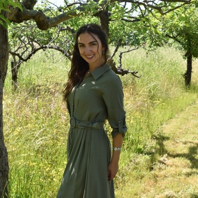 Mulher com vestido verde ao ar livre num campo com árvores e relva alta