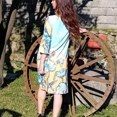 Vestido floral azul e bege usado por mulher ao ar livre junto a uma roda de madeira