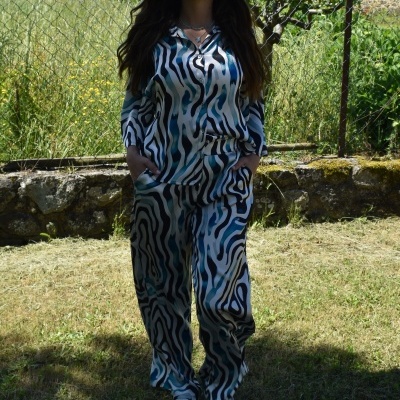 Mulher com macacão comprido azul, preto e branco em jardim