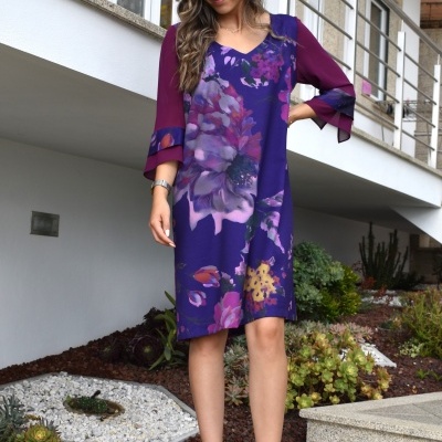 Vestido floral roxo com mangas vinho utilizado por mulher em área exterior.