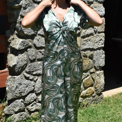 Vestido comprido de mulher com padrão verde e branco frente muro de pedra