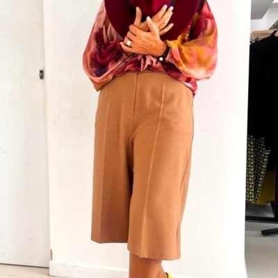 Mulher com roupa colorida e chapéu vermelho em ambiente interior