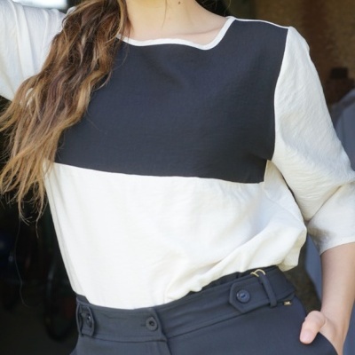 Mulher com blusa bicolor preta e branca e calças pretas de cintura alta