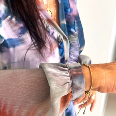 Camisa feminina tie-dye azul, laranja e branco com punho elástico franzido e acessórios dourados