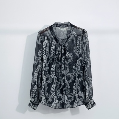 Blusa preta com padrão de correntes brancas e laço no pescoço