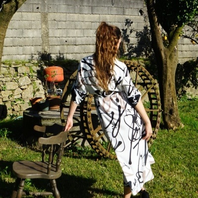 Vestido branco com padrão abstrato preto em jardim com cadeira de madeira