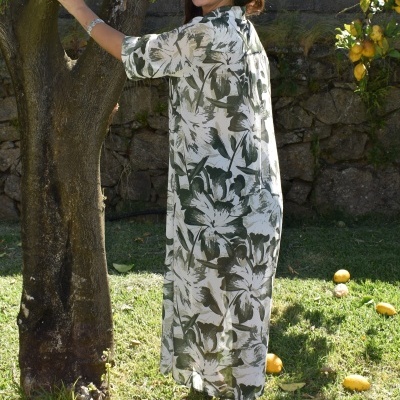 Vestido comprido floral verde e branco ao ar livre junto a árvore e limoeiros