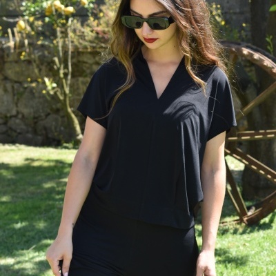 Mulher de óculos escuros em jardim a usar conjunto preto de camisola e calças largas