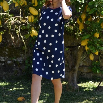 Vestido curto azul com bolinhas brancas em jardim com limões