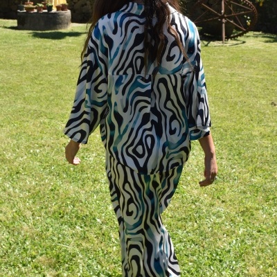 Pessoa com pijama com padrão abstrato colorido num jardim gramado