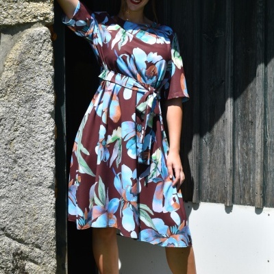 Vestido midi floral azul e castanho com cinto, em parede de pedra e madeira