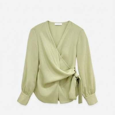 Blusa verde claro de mulher com laço e mangas compridas sobre fundo branco