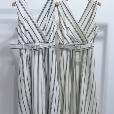 Dois vestidos às riscas com cintos brancos pendurados em cabides de madeira