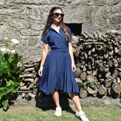 Vestido azul escuro com cinto e saia plissada em mulher ao ar livre