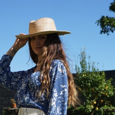 Mulher com chapéu de palha e camisa azul com padrão floral