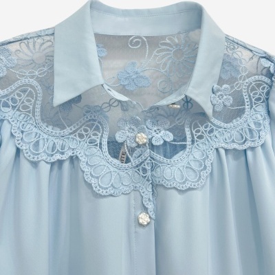 Camisa azul clara com renda floral bordada e botões decorativos em forma de flor