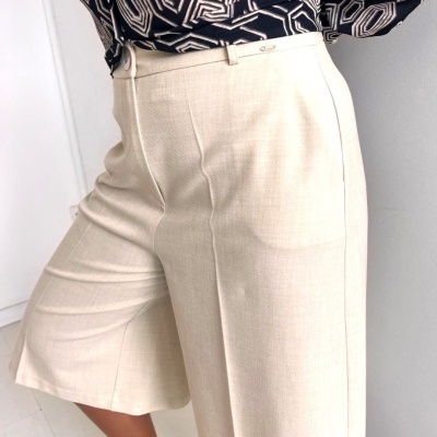 Calças compridas tipo bermuda bege claro com cinto fino e camisa preta e branca geométrica