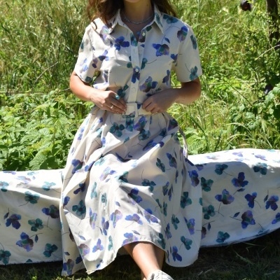 Vestido comprido floral azul e verde com botões e cinto, mulher sentada ao ar livre