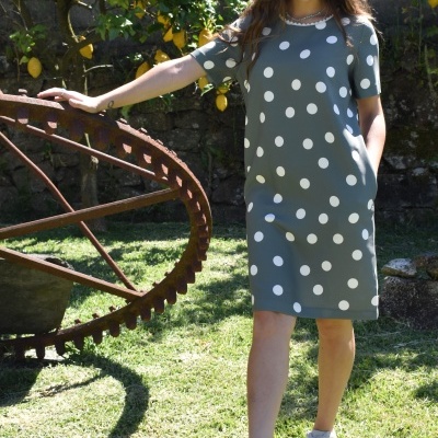 Mulher a usar vestido cinza com bolinhas brancas e sapatilhas brancas ao ar livre