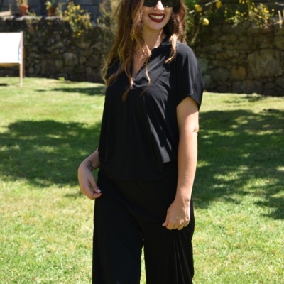 Mulher com vestido preto a usar óculos de sol no exterior em relvado