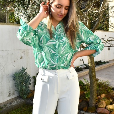 Pessoa a usar camisa verde com padrão de folhas e calças brancas ao ar livre