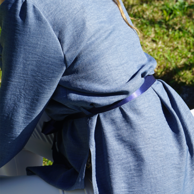 Casaco azul claro com cinto roxo usado em ambiente exterior