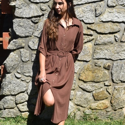 Vestido midi castanho com cinto e ténis brancos em parede de pedra